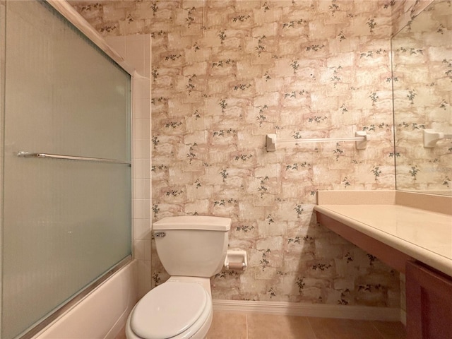 bathroom featuring toilet, shower / bath combination with glass door, and tile patterned flooring