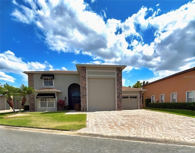 view of front of house featuring stucco siding, an attached garage, stone siding, decorative driveway, and a front lawn