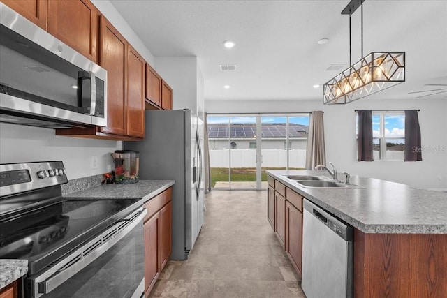 kitchen featuring a center island with sink, sink, hanging light fixtures, ceiling fan, and stainless steel appliances