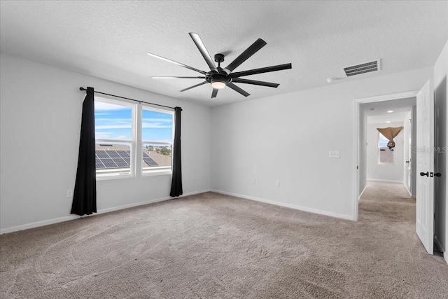 carpeted empty room with ceiling fan and a textured ceiling