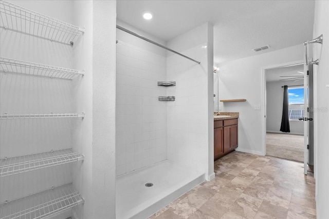 bathroom with a tile shower and vanity