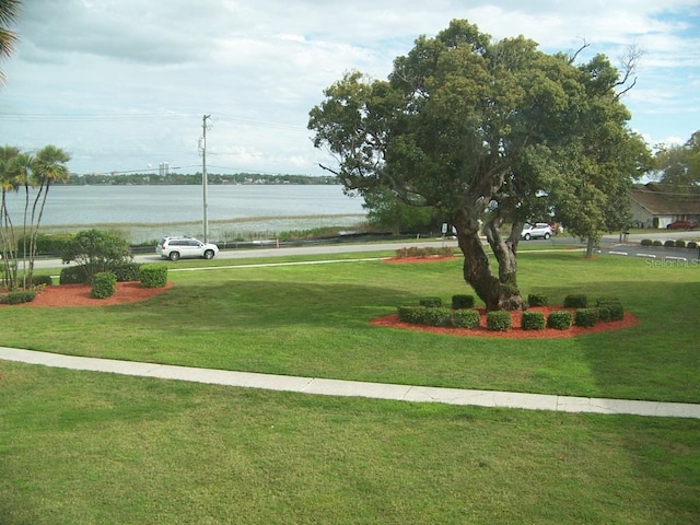 surrounding community with a water view and a lawn