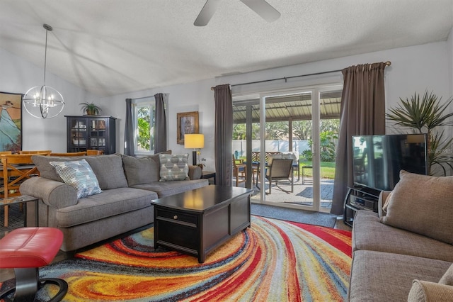 living room with vaulted ceiling, ceiling fan with notable chandelier, and a textured ceiling