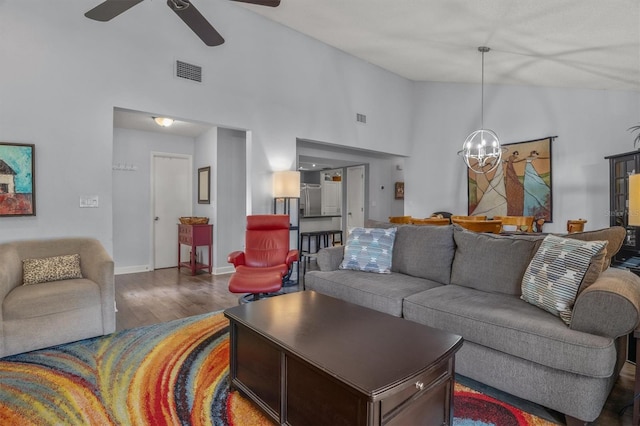 living room featuring ceiling fan with notable chandelier, dark hardwood / wood-style floors, and high vaulted ceiling