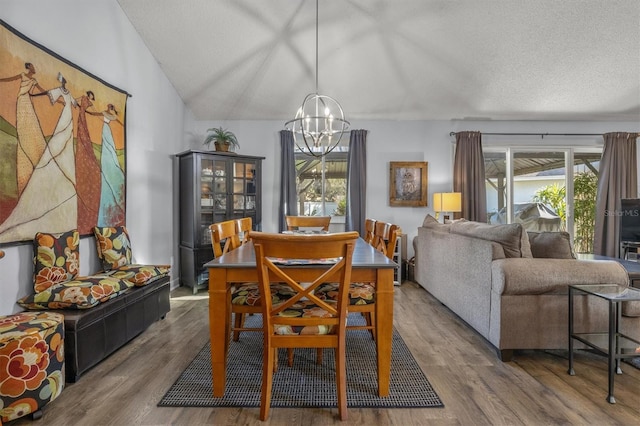 dining room featuring hardwood / wood-style flooring, a textured ceiling, a notable chandelier, and vaulted ceiling