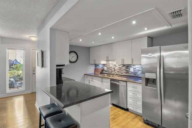 kitchen featuring a breakfast bar, sink, stainless steel appliances, and white cabinetry