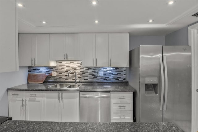 kitchen with stainless steel appliances, backsplash, dark stone counters, white cabinets, and sink