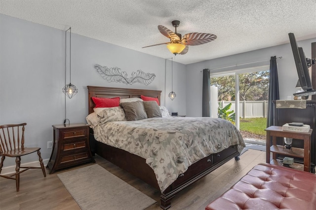 bedroom featuring a textured ceiling, ceiling fan, access to exterior, and light hardwood / wood-style floors