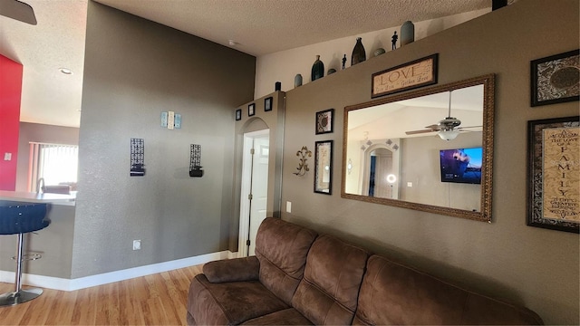 living room with ceiling fan, a textured ceiling, and light hardwood / wood-style flooring