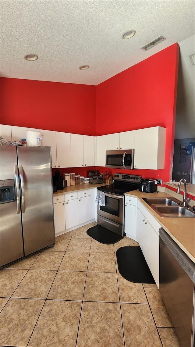 kitchen featuring light tile patterned flooring, stainless steel appliances, sink, and white cabinets