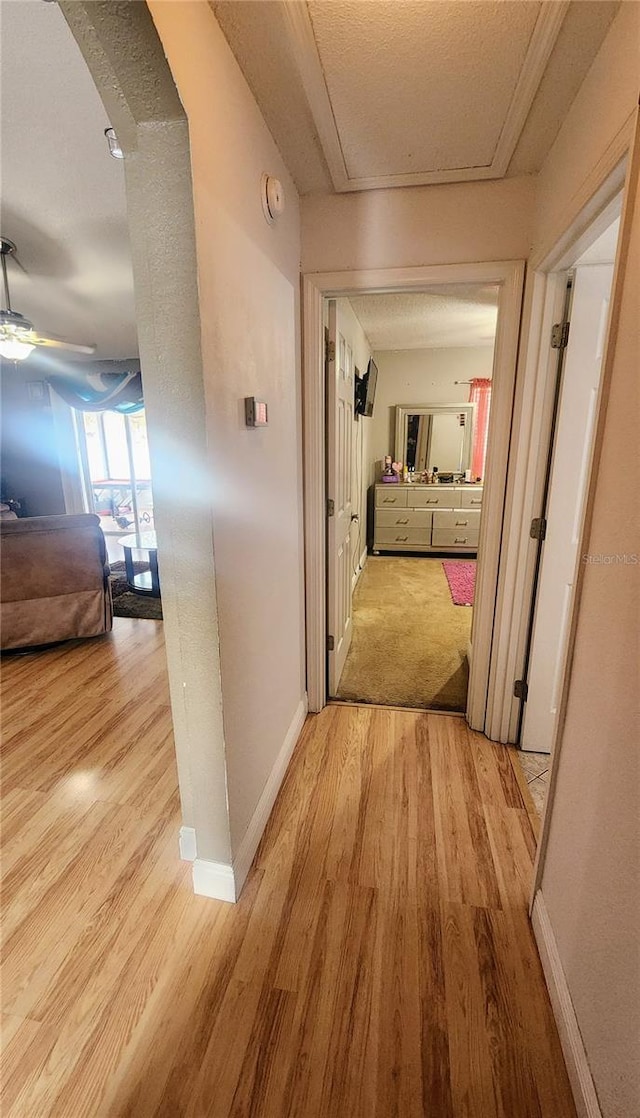 hall featuring a textured ceiling and light hardwood / wood-style flooring