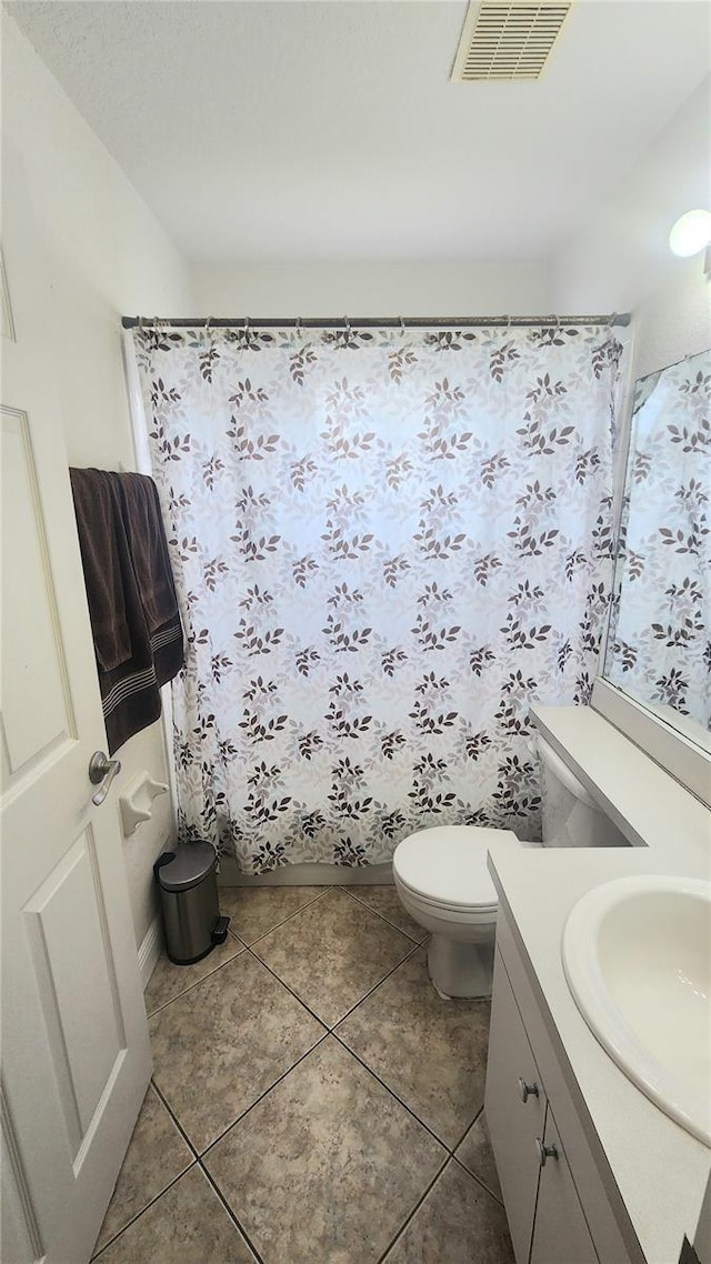 bathroom featuring vanity, walk in shower, tile patterned floors, and toilet