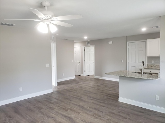 kitchen with dark hardwood / wood-style flooring, light stone countertops, sink, and white cabinets