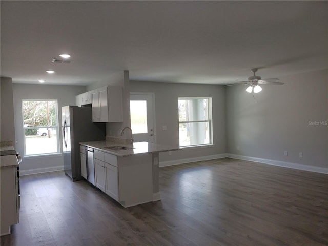 kitchen with sink, appliances with stainless steel finishes, white cabinetry, light stone countertops, and dark hardwood / wood-style flooring