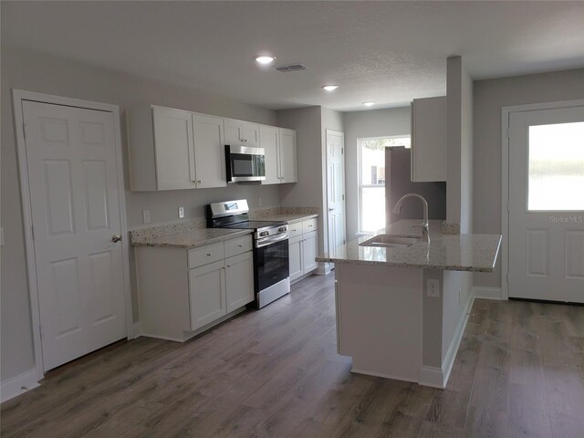 kitchen featuring sink, hardwood / wood-style flooring, appliances with stainless steel finishes, white cabinetry, and light stone countertops