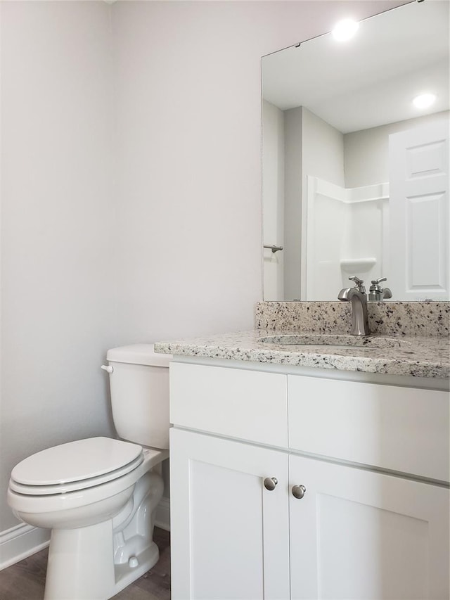 bathroom featuring vanity, wood-type flooring, toilet, and walk in shower