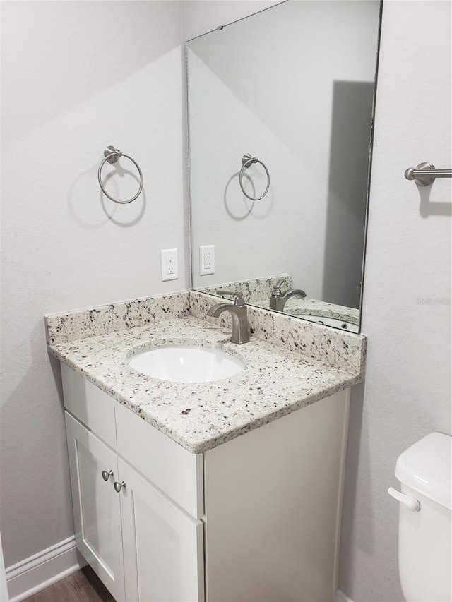 bathroom with vanity, toilet, and hardwood / wood-style floors