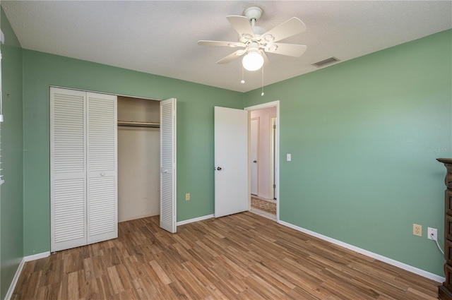 unfurnished bedroom with light wood-type flooring, ceiling fan, a textured ceiling, and a closet