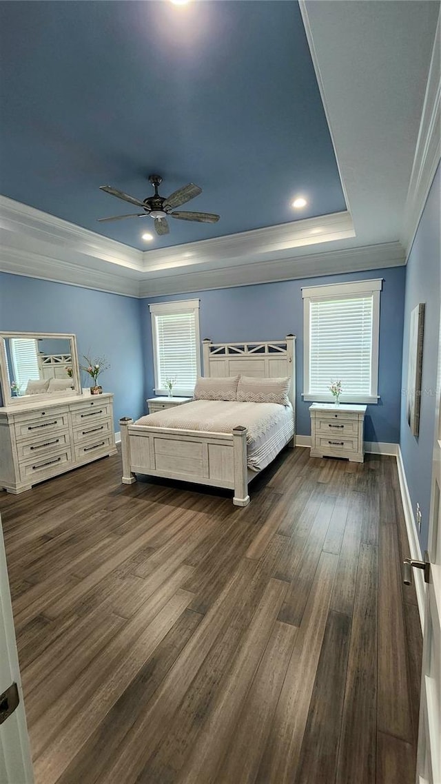 unfurnished bedroom featuring ceiling fan, dark hardwood / wood-style flooring, ornamental molding, and a tray ceiling