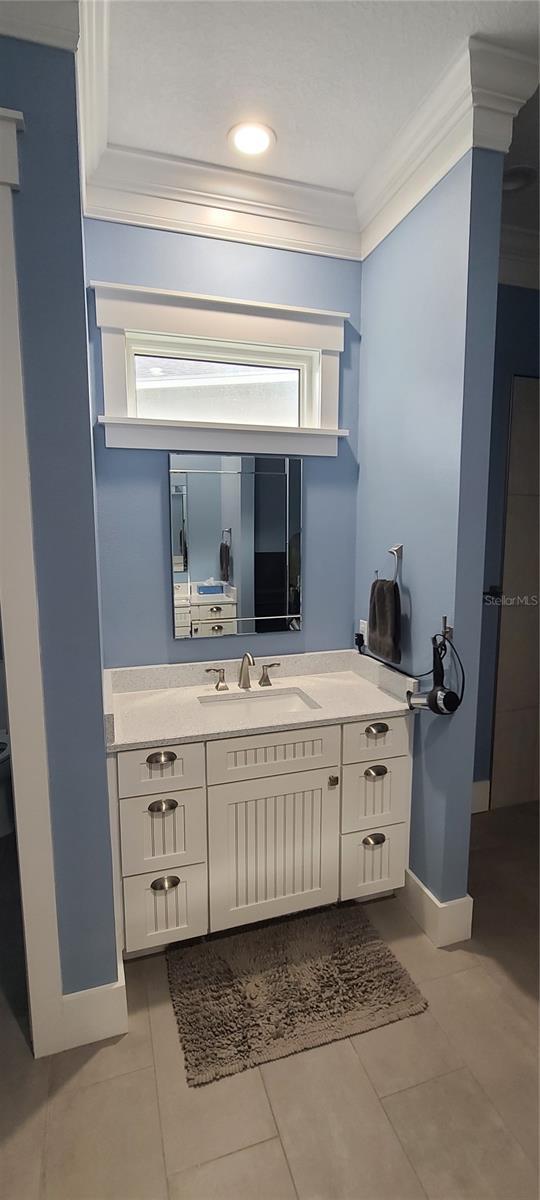 bathroom with ornamental molding, vanity, and tile patterned floors