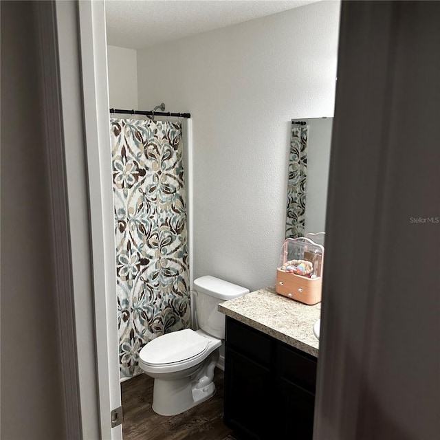 bathroom with toilet, a shower with shower curtain, vanity, hardwood / wood-style flooring, and a textured ceiling