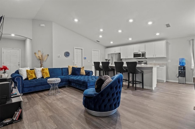 living room featuring light hardwood / wood-style floors and high vaulted ceiling