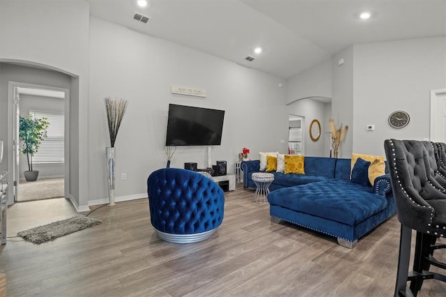 living room featuring high vaulted ceiling and wood-type flooring