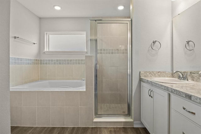 bathroom with hardwood / wood-style floors, vanity, and separate shower and tub