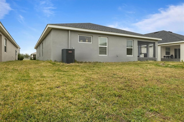 rear view of house with central air condition unit and a yard