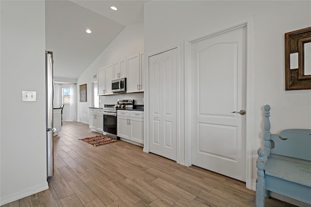 kitchen featuring white cabinets, appliances with stainless steel finishes, and vaulted ceiling