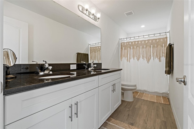 bathroom featuring toilet, wood-type flooring, vanity, and walk in shower