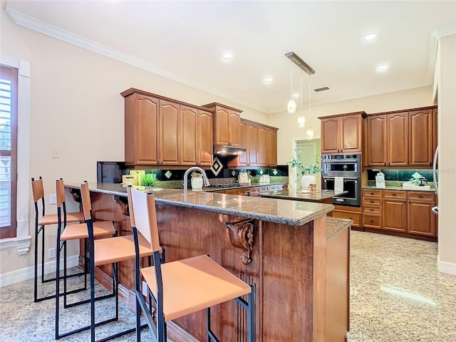 kitchen featuring stainless steel double oven, dark stone countertops, a kitchen breakfast bar, backsplash, and kitchen peninsula