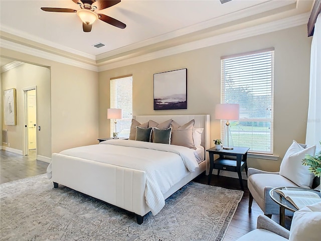 bedroom featuring ceiling fan, a raised ceiling, crown molding, and hardwood / wood-style flooring