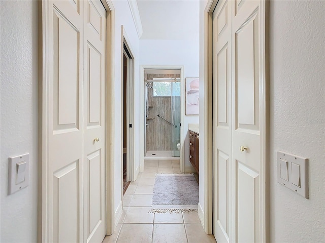 corridor with light tile patterned flooring and crown molding