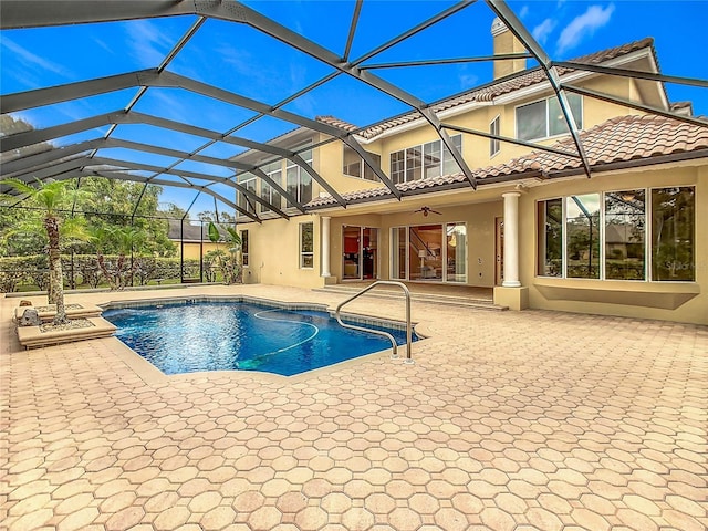 view of swimming pool with ceiling fan, glass enclosure, and a patio area