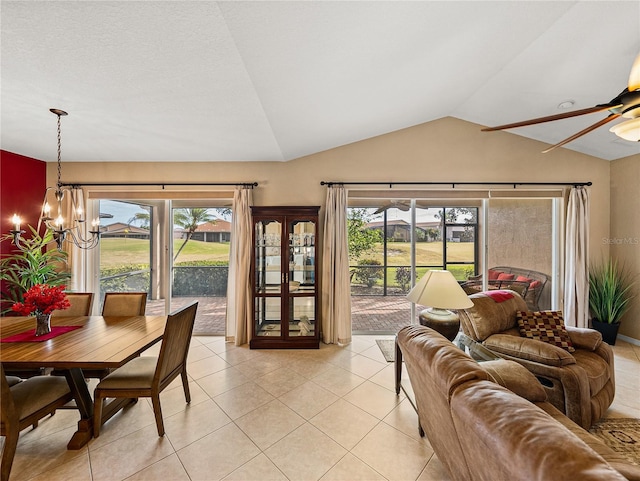 tiled living room featuring vaulted ceiling, a wealth of natural light, and ceiling fan with notable chandelier