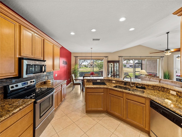 kitchen featuring lofted ceiling, pendant lighting, sink, appliances with stainless steel finishes, and ceiling fan with notable chandelier