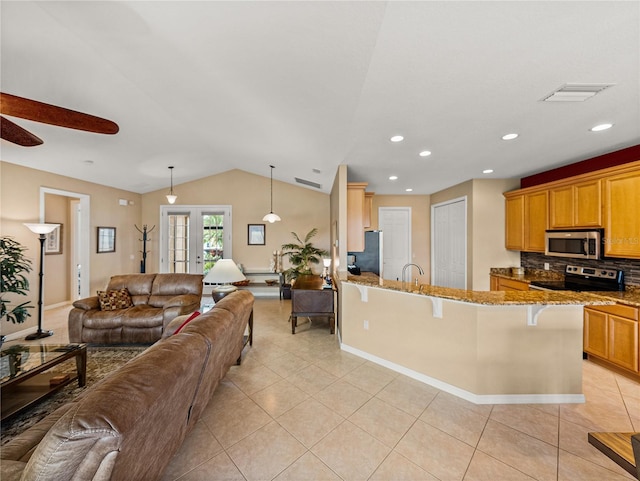 kitchen with decorative light fixtures, vaulted ceiling, kitchen peninsula, a breakfast bar area, and stainless steel appliances