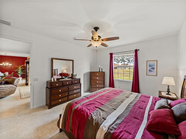 carpeted bedroom featuring ceiling fan with notable chandelier