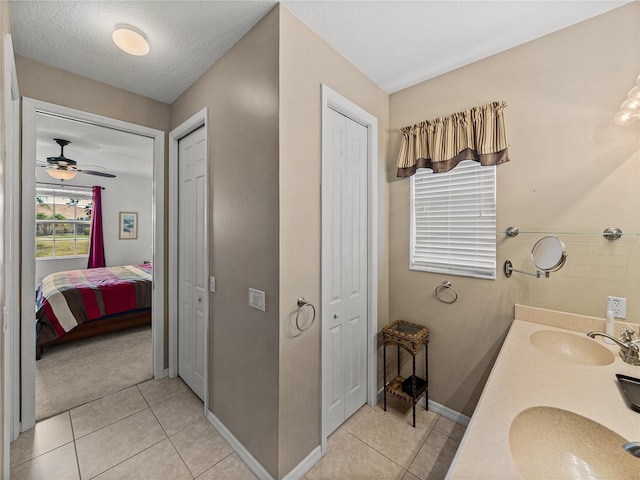 bathroom with ceiling fan, a textured ceiling, vanity, and tile patterned flooring