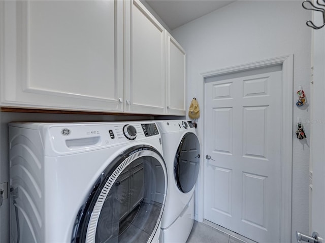 laundry room with cabinets, light tile patterned floors, and washing machine and clothes dryer