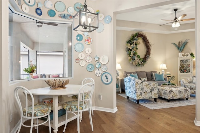 dining area featuring ceiling fan with notable chandelier and dark hardwood / wood-style floors