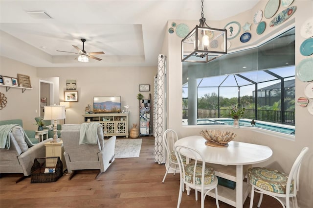 dining area with ceiling fan, hardwood / wood-style floors, and a tray ceiling