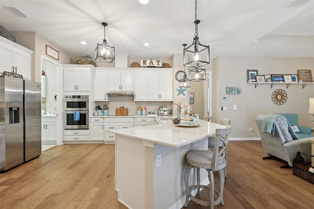 kitchen with decorative light fixtures, appliances with stainless steel finishes, sink, and white cabinetry