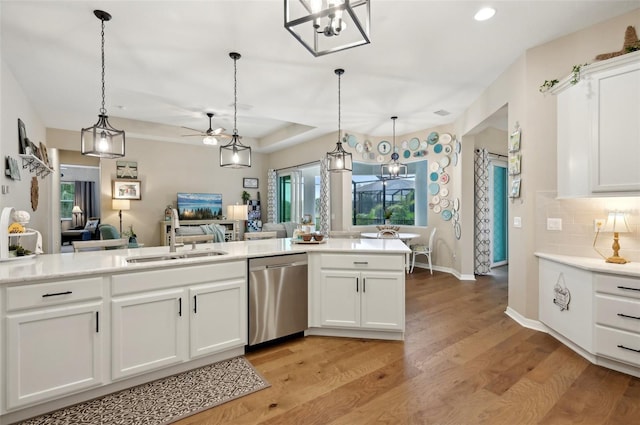 kitchen featuring white cabinets, dishwasher, decorative light fixtures, sink, and light wood-type flooring