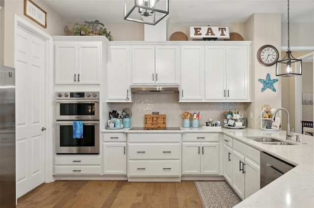 kitchen featuring white cabinetry, appliances with stainless steel finishes, tasteful backsplash, decorative light fixtures, and sink