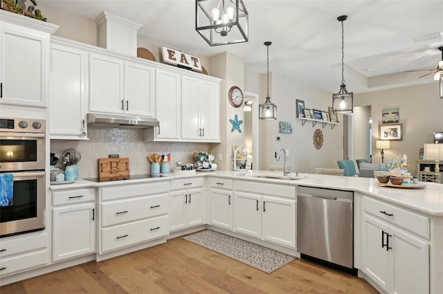 kitchen featuring pendant lighting, appliances with stainless steel finishes, white cabinetry, sink, and backsplash