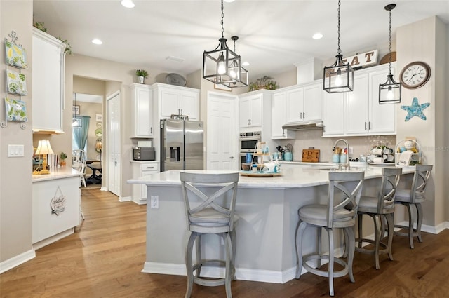 kitchen with kitchen peninsula, stainless steel refrigerator with ice dispenser, white cabinetry, and pendant lighting