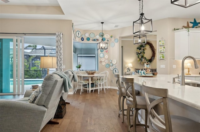 kitchen featuring pendant lighting, a kitchen bar, hardwood / wood-style flooring, and sink