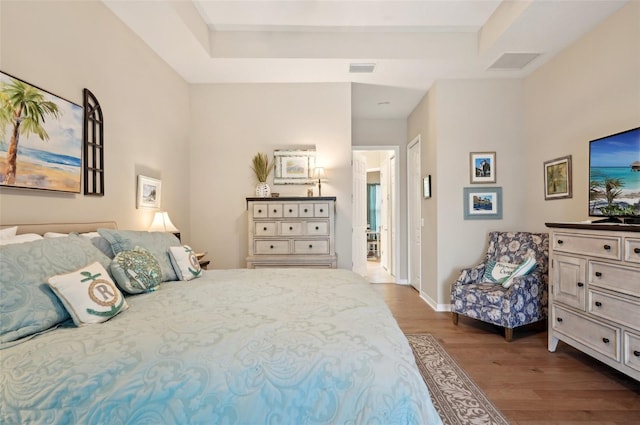 bedroom with light hardwood / wood-style flooring and a tray ceiling